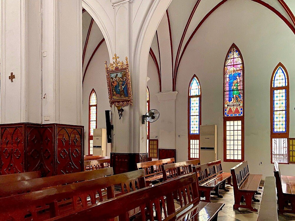 Inside the cathedral, warm light filters through stained glass, filling the space with quiet beauty